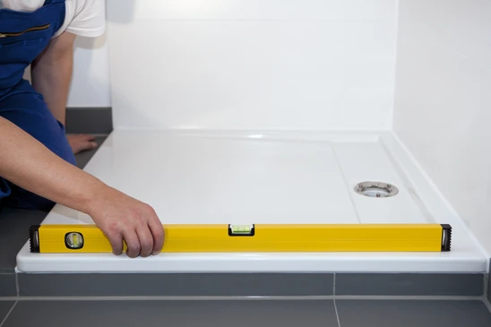 Salle de bains moderne avec ouvrier installant un receveur de douche blanc
