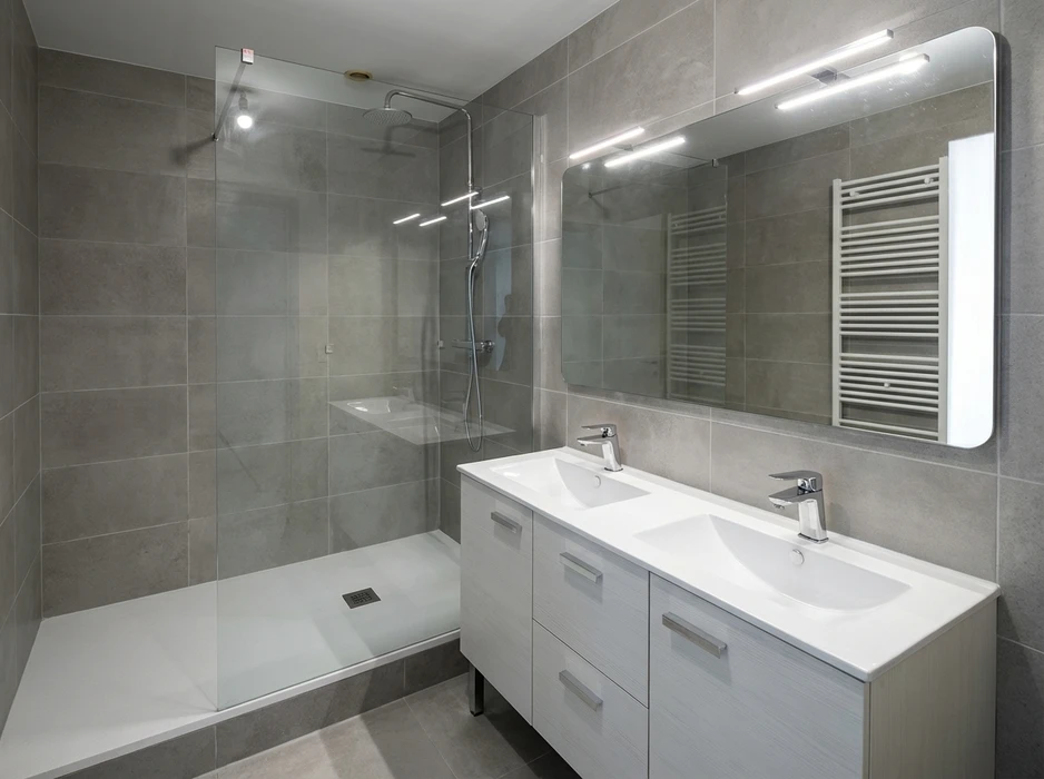 Salle de bains moderne avec douche à l'italienne en verre, receveur blanc bas, colonne de douche thermostatique chromée et pommeau de tête fixe
