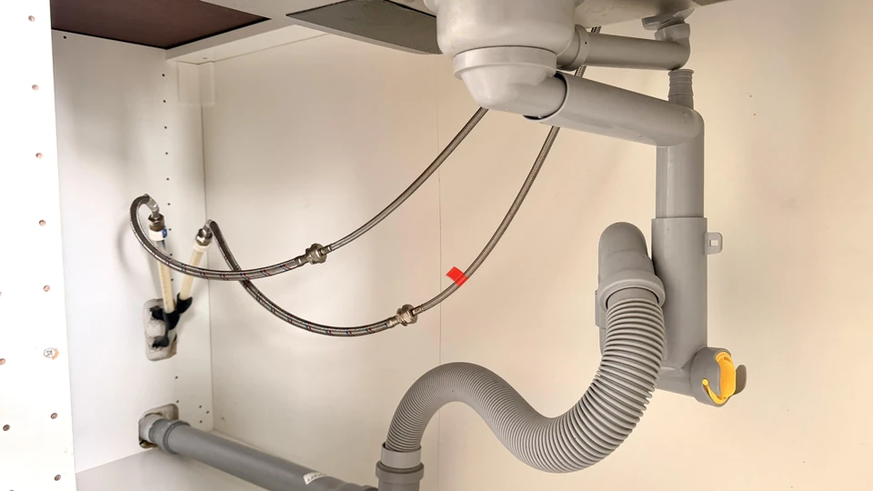 Technicien en salopette bleue effectuant la maintenance d'un radiateur à ailettes dans un intérieur résidentiel moderne