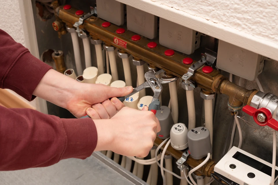 Un technicien en uniforme effectue la maintenance d'une chaudière à gaz domestique