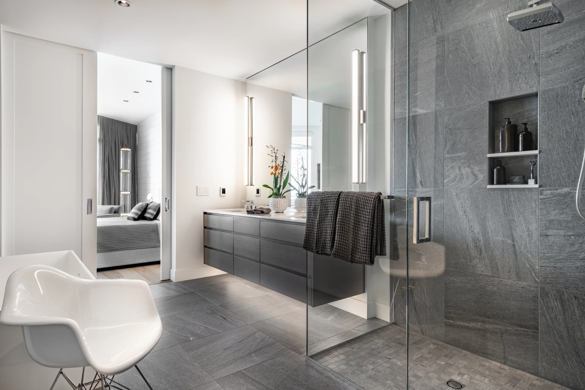 Salle de bain moderne avec double vasque sur meuble suspendu en bois strié, deux miroirs ronds à cadre doré, baignoire îlot blanche