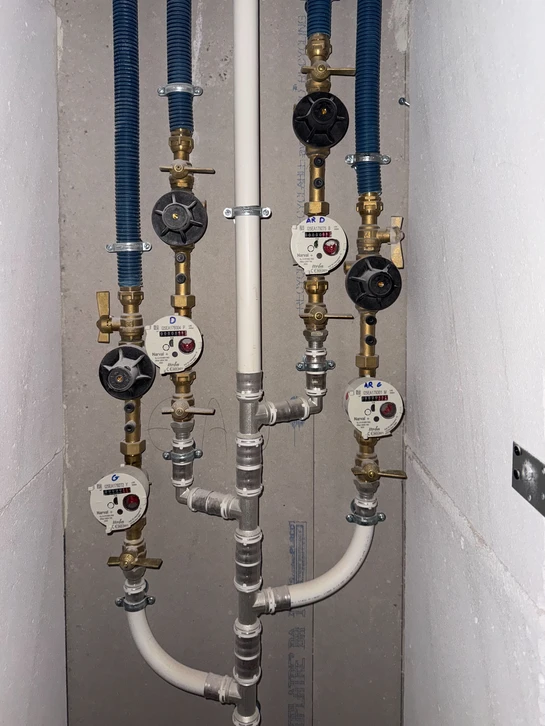 Technicien en salopette bleue effectuant la maintenance d'un radiateur &agrave; ailettes dans un int&eacute;rieur r&eacute;sidentiel moderne